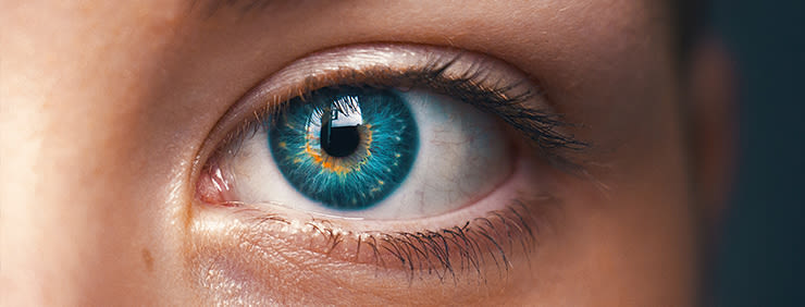 Close-up of a vibrant blue human eye with intricate details of the iris and surrounding skin.
