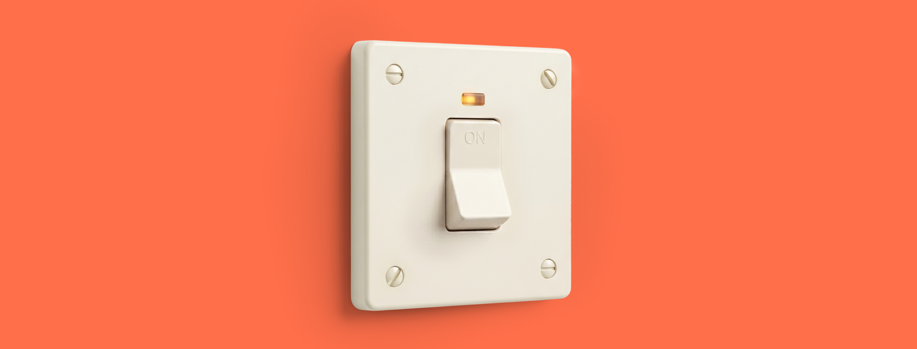 A white light switch in the on position is mounted on a coral-orange background, with a small amber indicator light glowing above it.