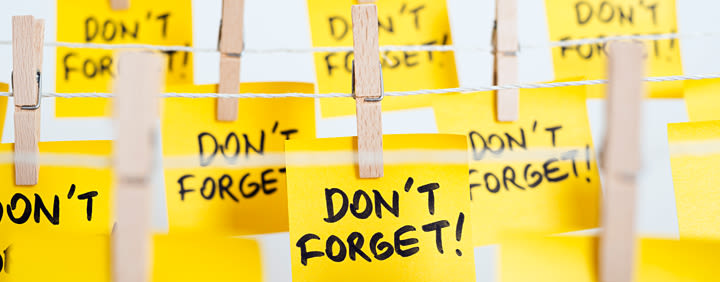 Yellow sticky notes hanging on a line with wooden clothespins, each displaying the handwritten message "DON'T FORGET!".