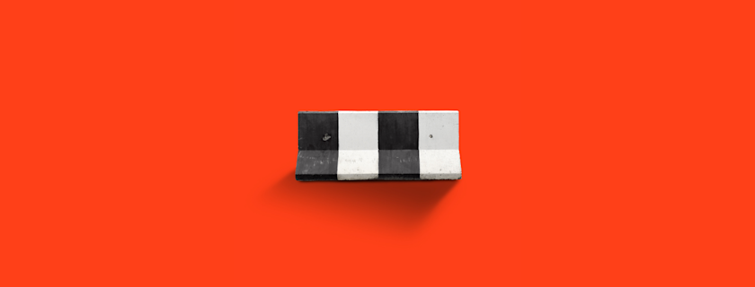 A black and white striped concrete barrier stands against a bright red background.