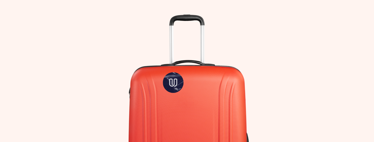 An orange suitcase with a retractable handle and a round sticker with a stylized 'U' inside.