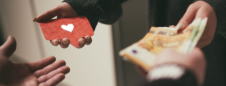 Hand exchanging a red speech bubble with a white heart for cash.