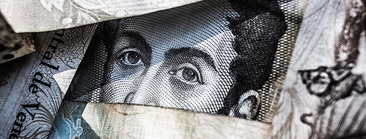 Close-up of a face, partially obscured by currency, with intense eyes peeking through the gaps.