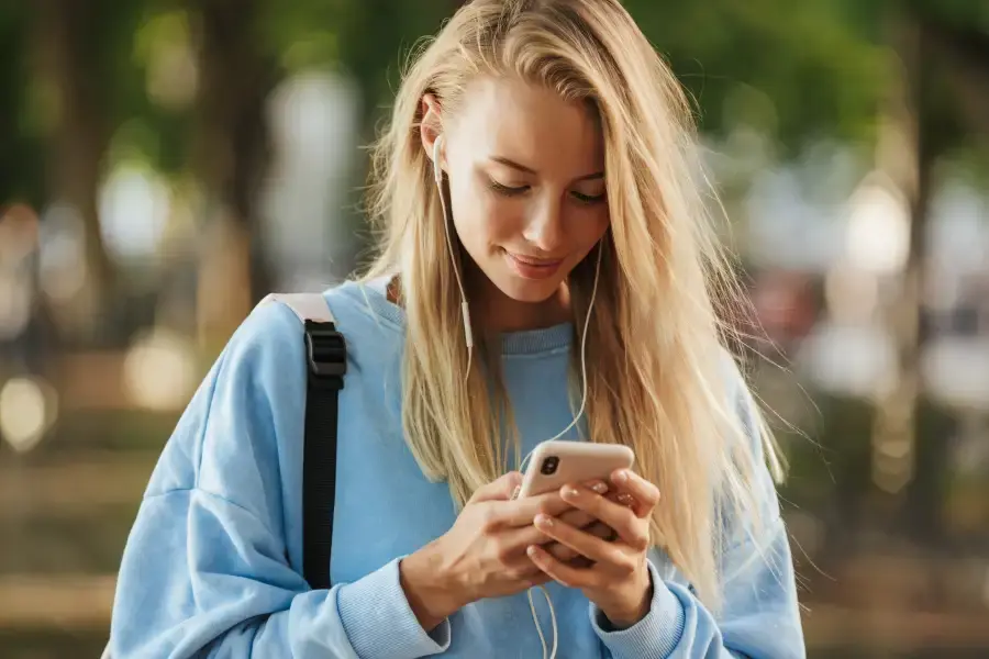 Teenage girl with headphones using mobile phone