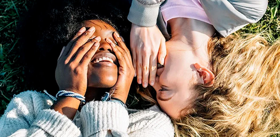 Two laughing girls laying on the grass