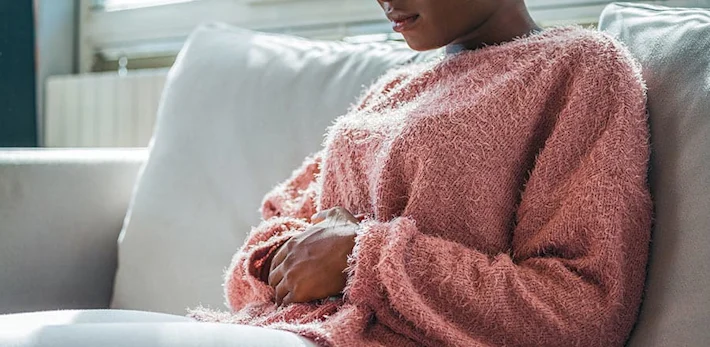 Woman with stomach pain is holding her aching belly