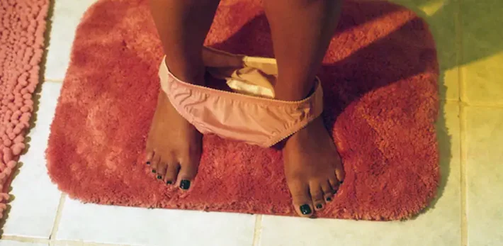 Woman with panties around her ankles sitting on toilet