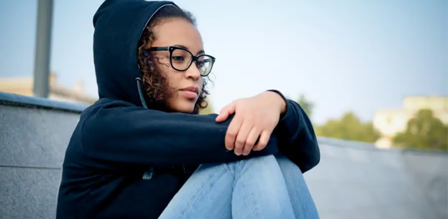 Teenage girl in glasses sitting on the ground