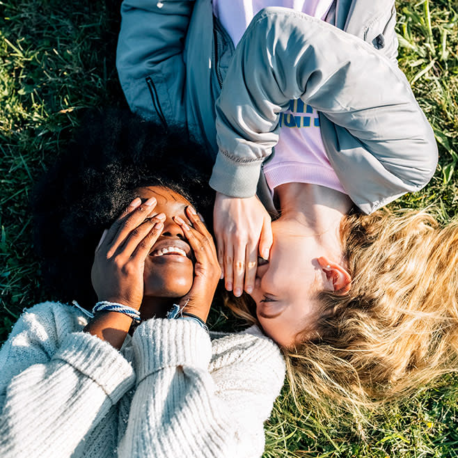 Two laughing girls laying on the grass