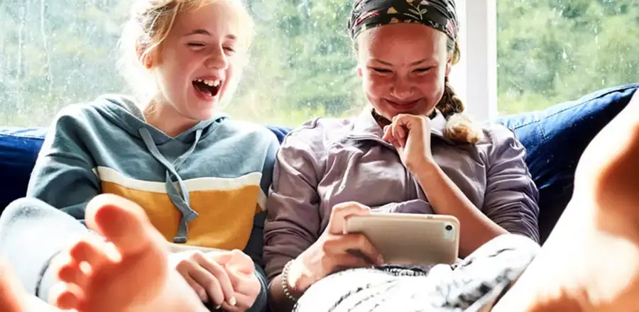 Two laughing teenage girls watching something on a smartphone