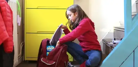 Teenage girl packing her school backpack