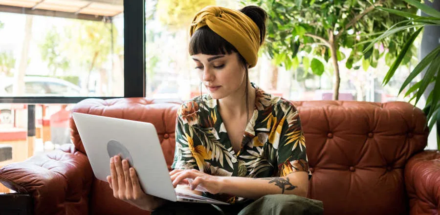 Teen girl sitting on sofa and using laptop computer