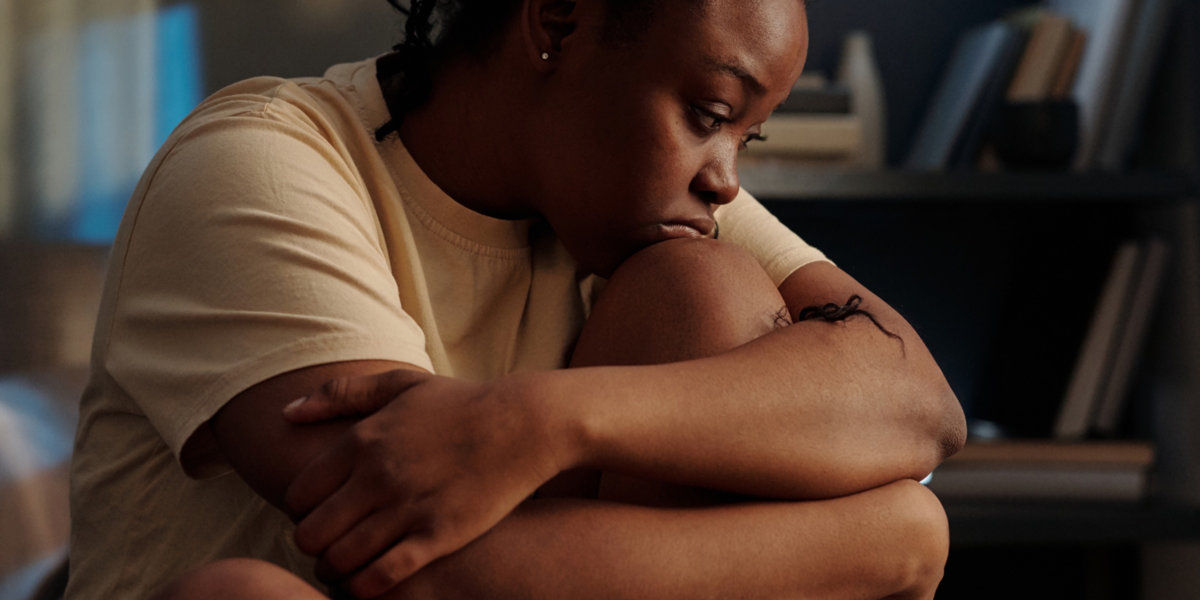Woman looking sat and sat hugging her knees