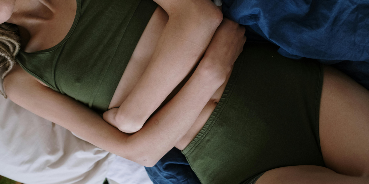 Une personne allongée sur le dos, les mains posées sur l’abdomen.