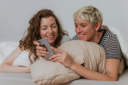 an image of two people on a bed looking at a phone