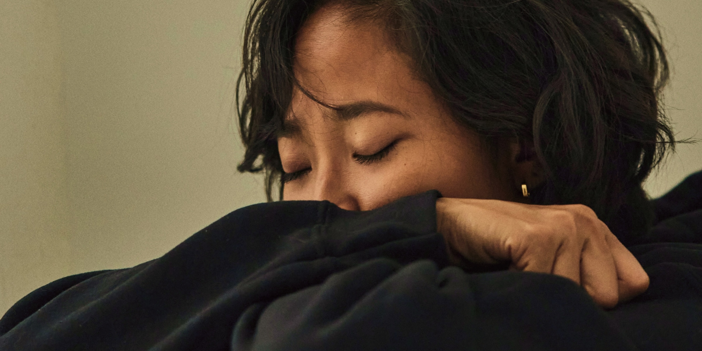 a woman in distress wearing a black sweater and covering her face with her hands, the Clue app logo in the corner 