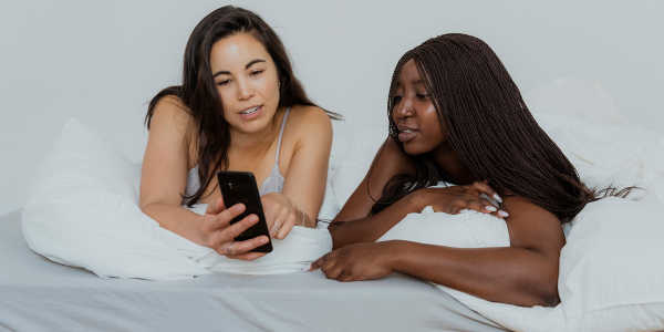 Duas garotas olhando o Clue app no celular, na cama