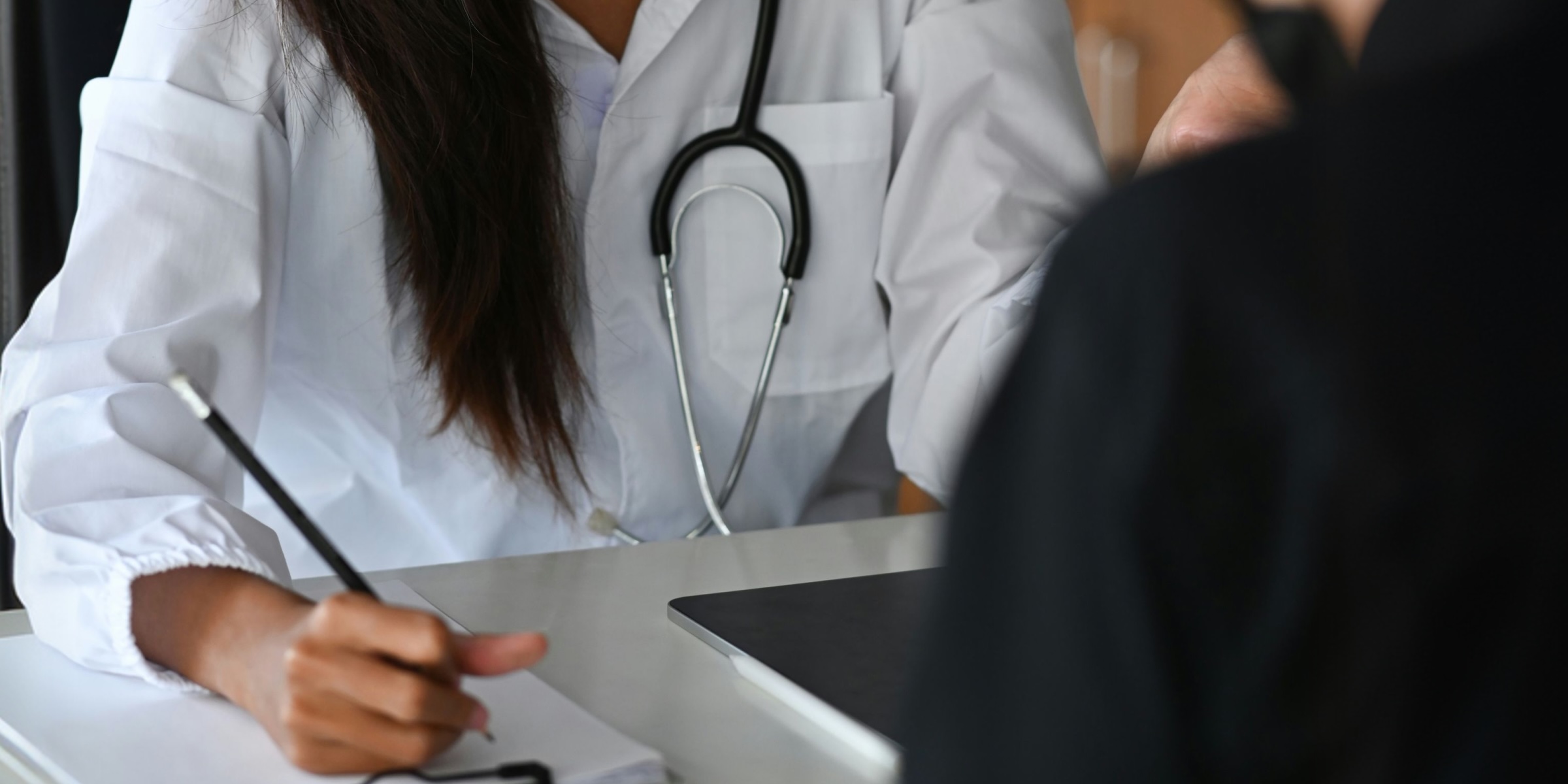 doctor with a notebook and pen seeing a patient 