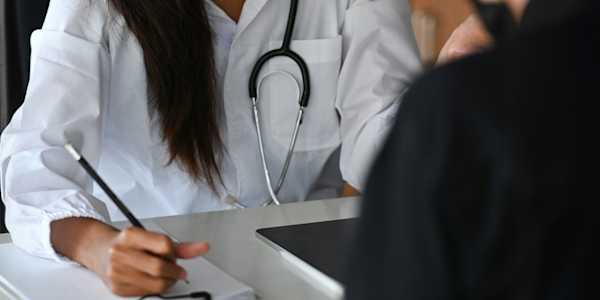 doctor with a notebook and pen seeing a patient