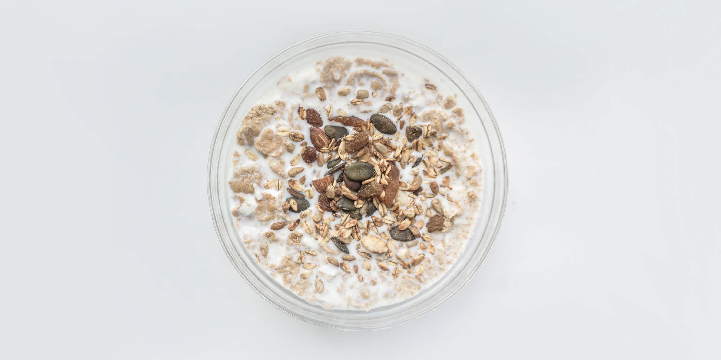Pumpkin seeds and almonds on top of granola, in a glass of milk. 