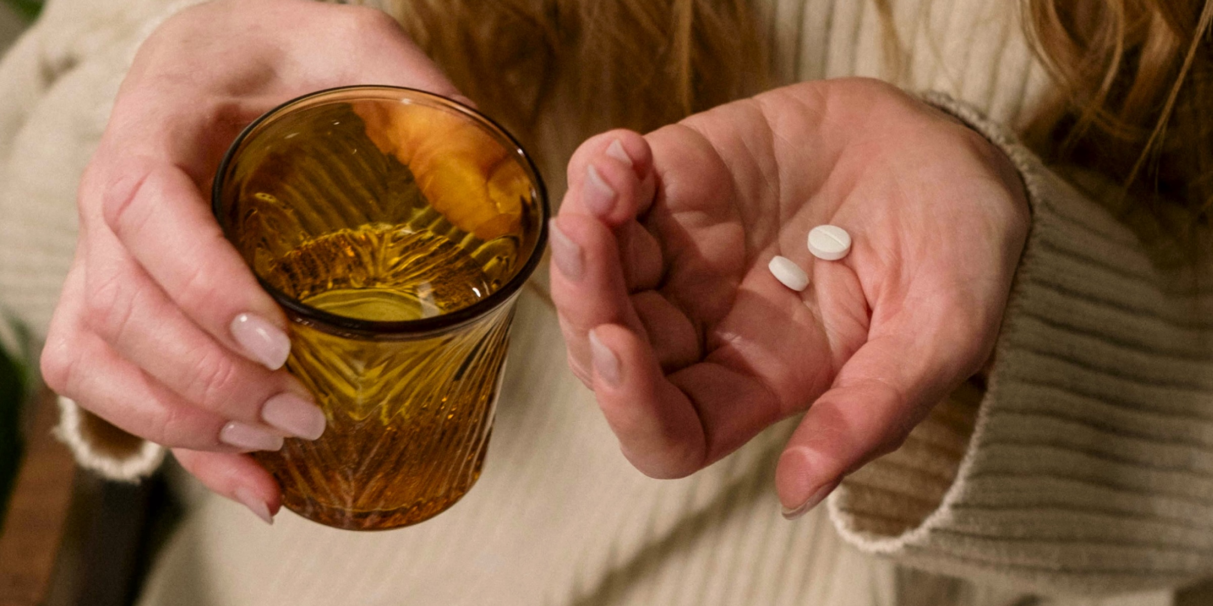 a hand with magnesium supplements and glass of water