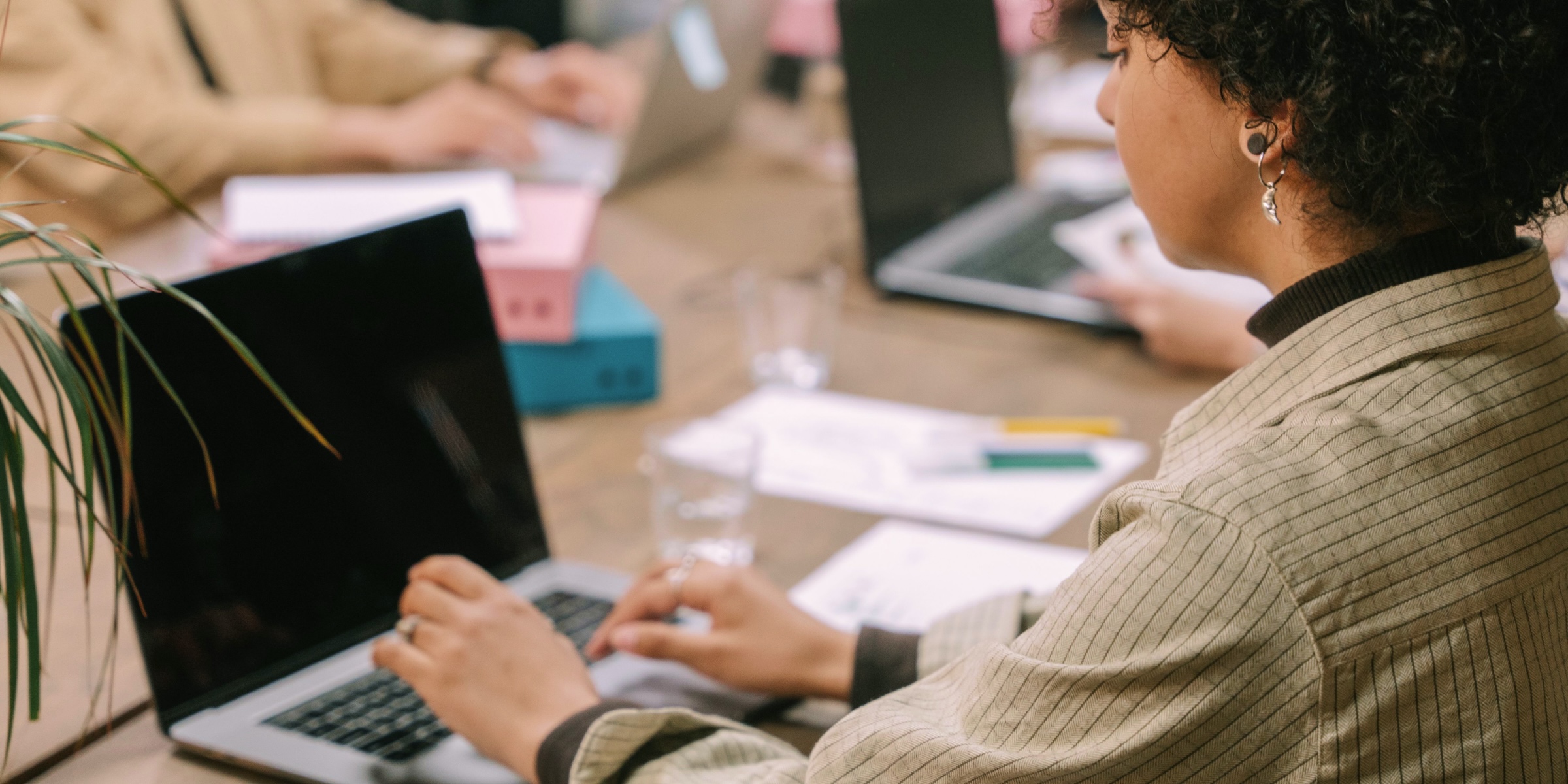 A woman sat at her desk at worktyping on a laptop