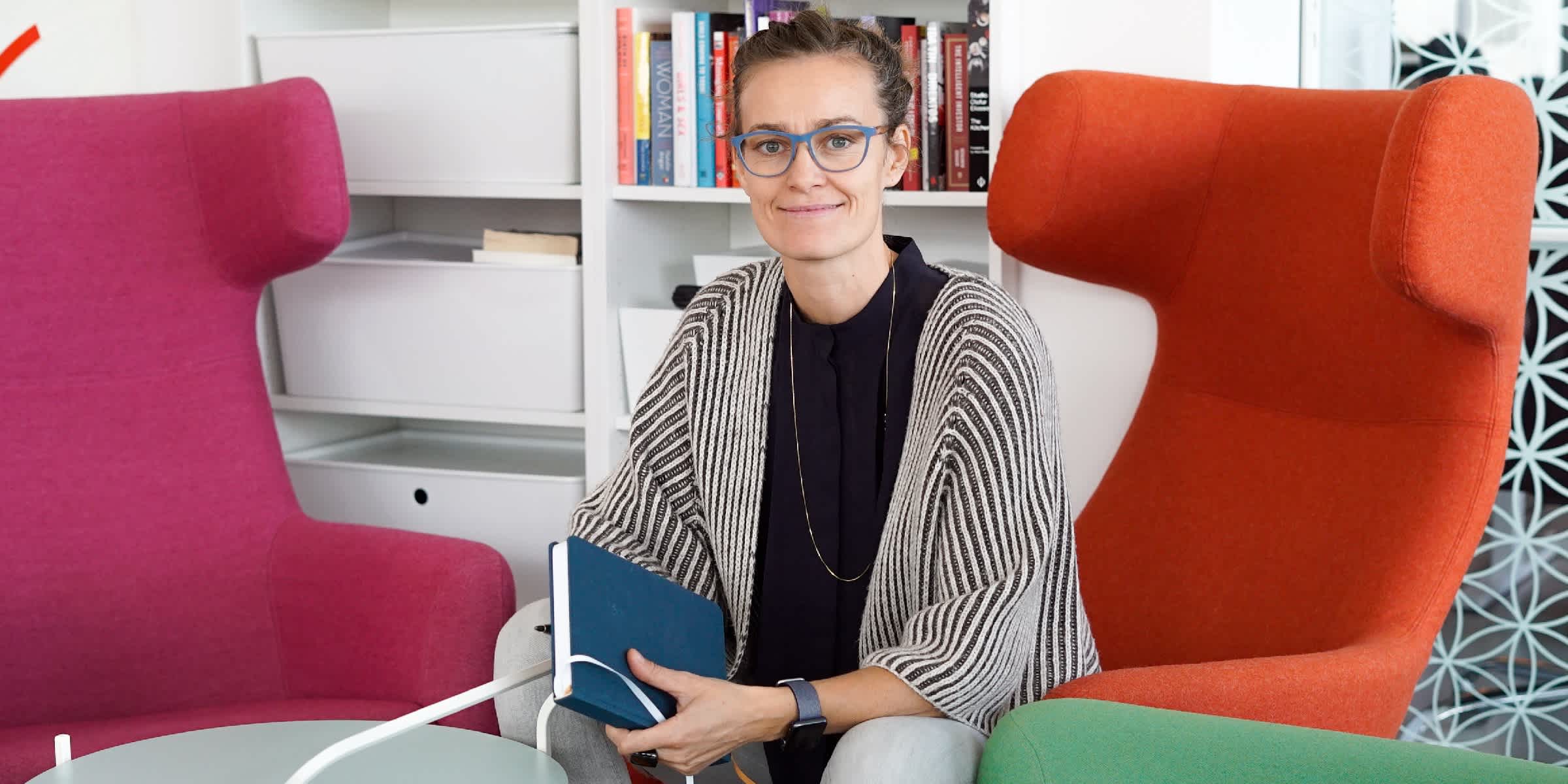 CEO of Clue Ida Tin sitting in her office holding a notebook.