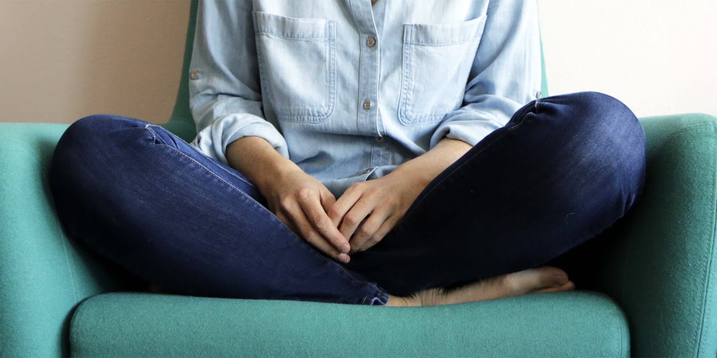 Mujer vestida informalmente sentada en una silla con las manos juntas