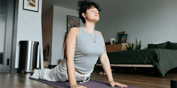Woman on a yoga matt doing a stretch in her bedrroom