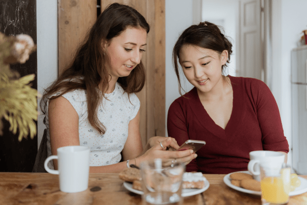 An image of two people looking at a phone over a breakfast table