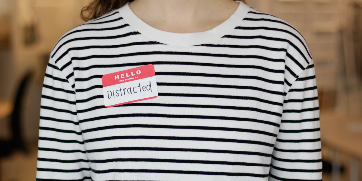 close up photograph of a woman wearing a striped shirt and a stickers saying hello my name is distracted in front of a blurry background