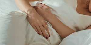 A woman lying in bed holding stomach in pain