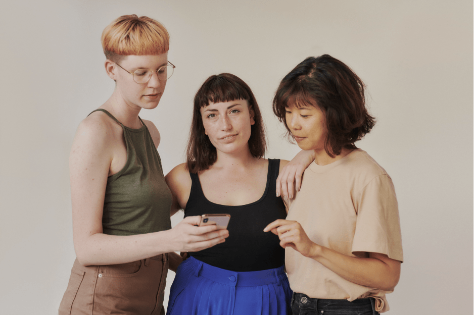 a picture of three people stood together looking at a phone