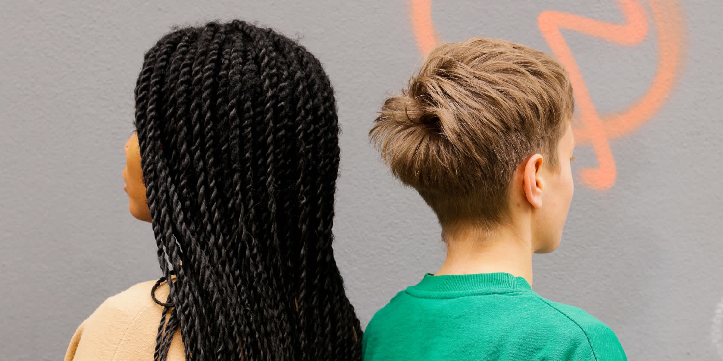 Foto de dos personas de pie espalda con espalda con el pelo