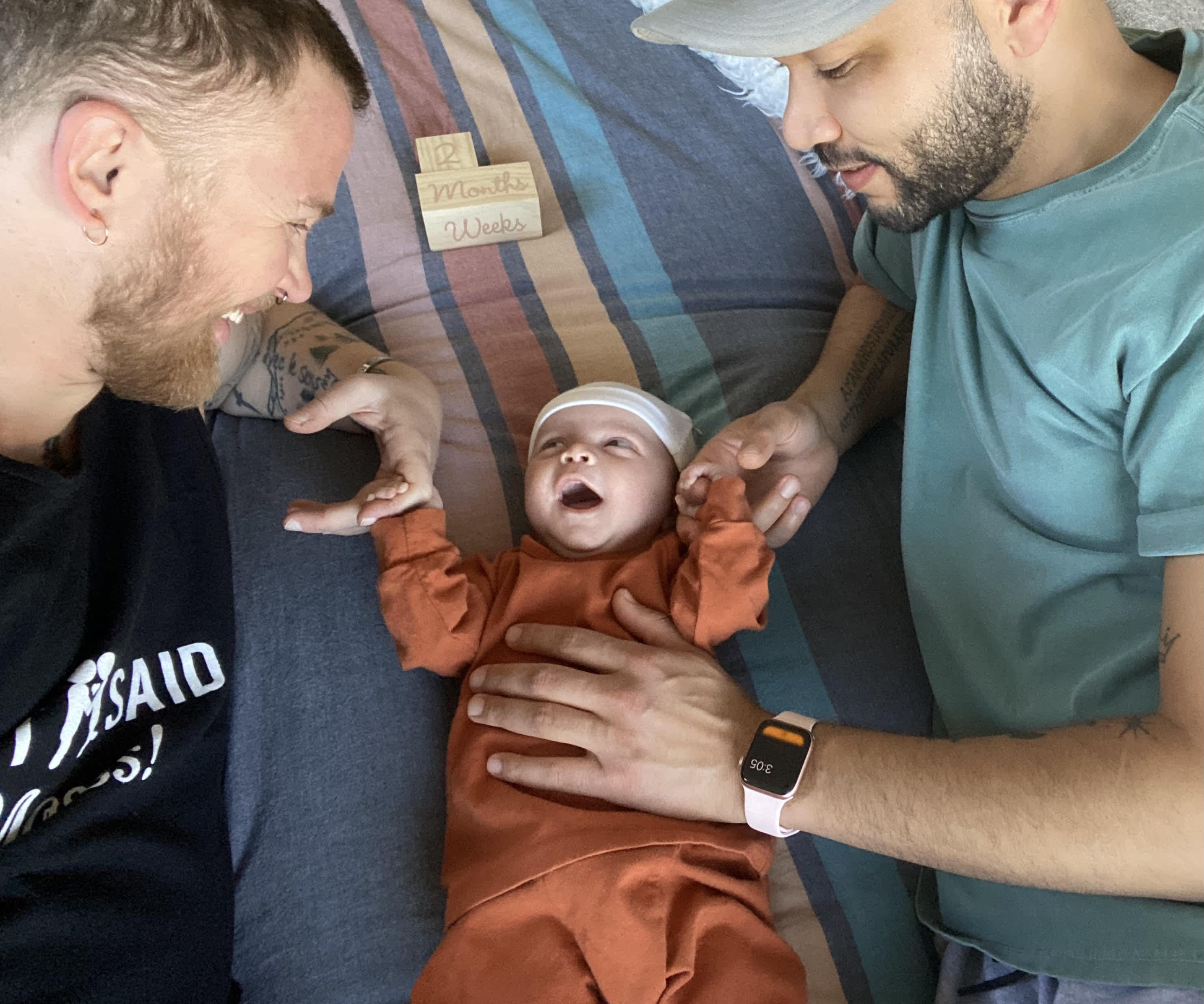 A photo of Bennett Kaspar-Williams and his husband Malik with their baby. 