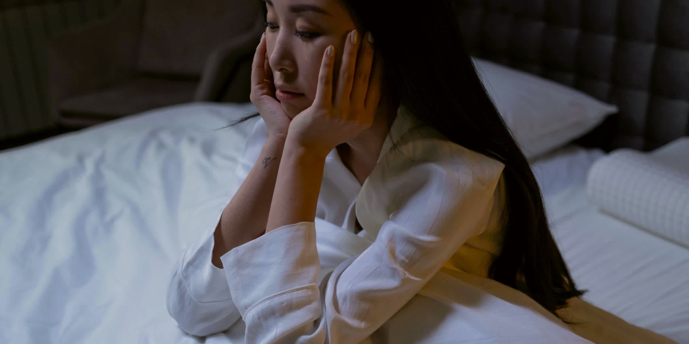 Woman sitting up in bed with her head in her hands