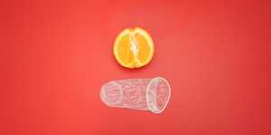 Préservatif féminin non emballé, illustré à côté d'une orange pour une perspective de taille.