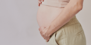 An image of a pregnant person with their hands on their belly