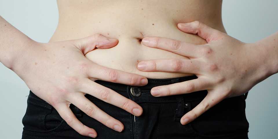 person experiencing period cramps with hands on stomach