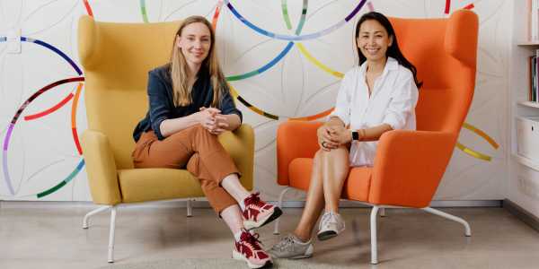 Clue's Co-CEOs sit in two chairs, smiling and facing the camera.