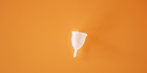 photograph of transparent menstrual cup on an orange surface