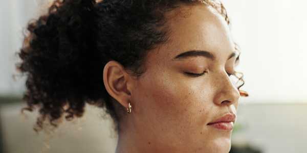 close up of a woman with curly hair and her eyes closed