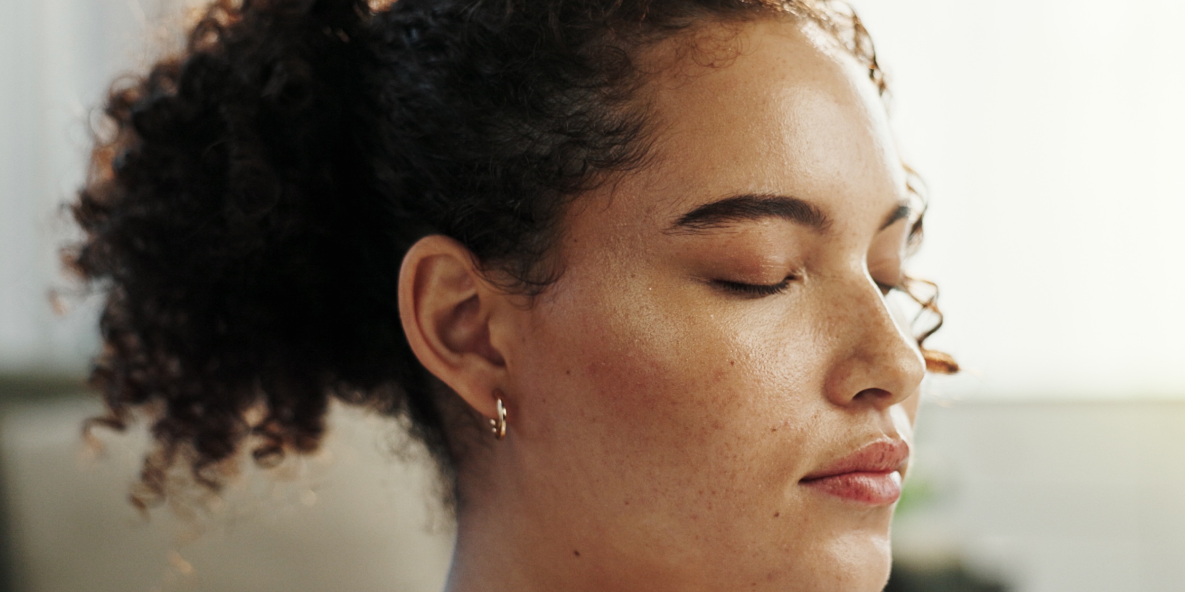 close up of a woman with curly hair and her eyes closed