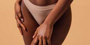 Close-up of a person in nude-colored underwear with hands on their thighs, illustrating an article about vaginismus