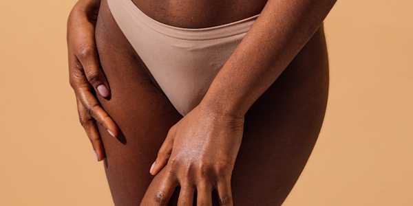 Close-up of a person in nude-colored underwear with hands on their thighs, illustrating an article about vaginismus