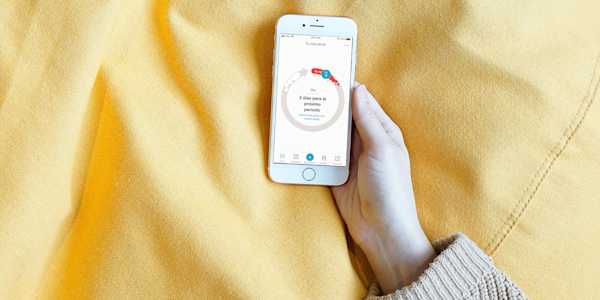 An image of a white person's hand holding a smartphone with Clue's cycle view visible.