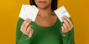 A woman holds two disposable menstrual pads in her hands. 