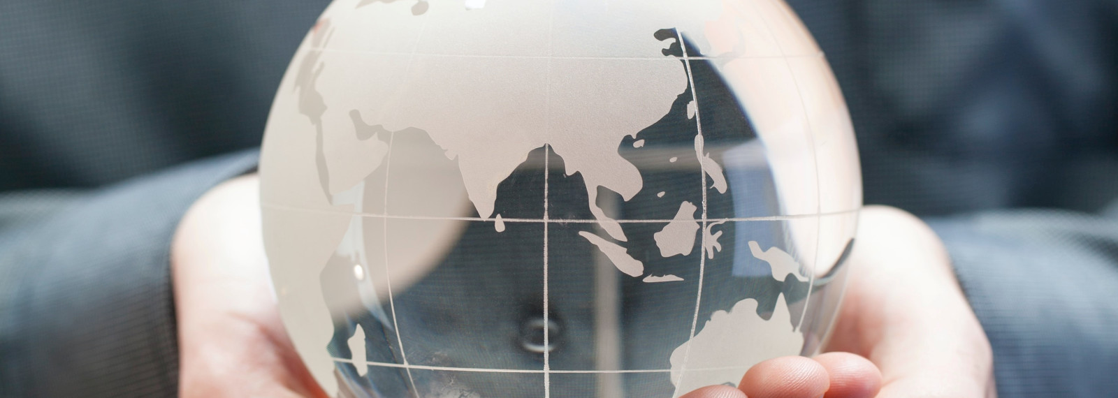 Image of hands holding a semi-transparent glass globe model