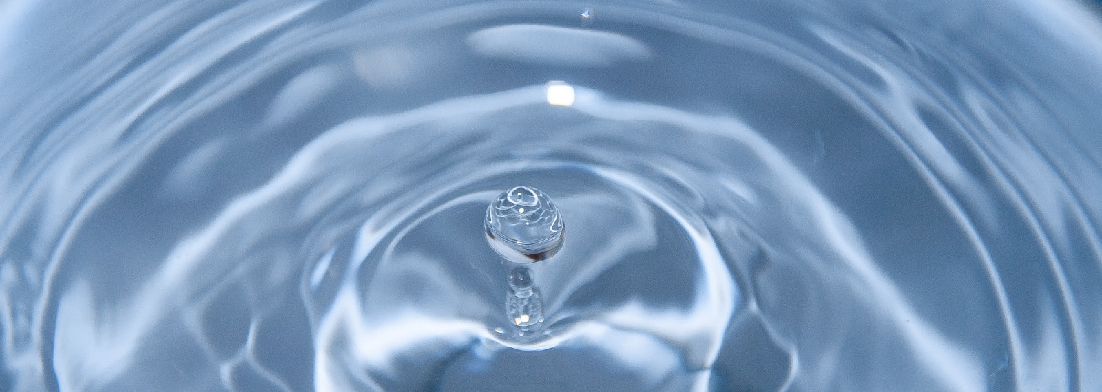 Image of spherical water droplet falling into water
