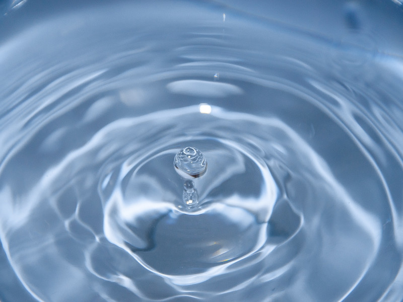Image of spherical water droplet falling into water
